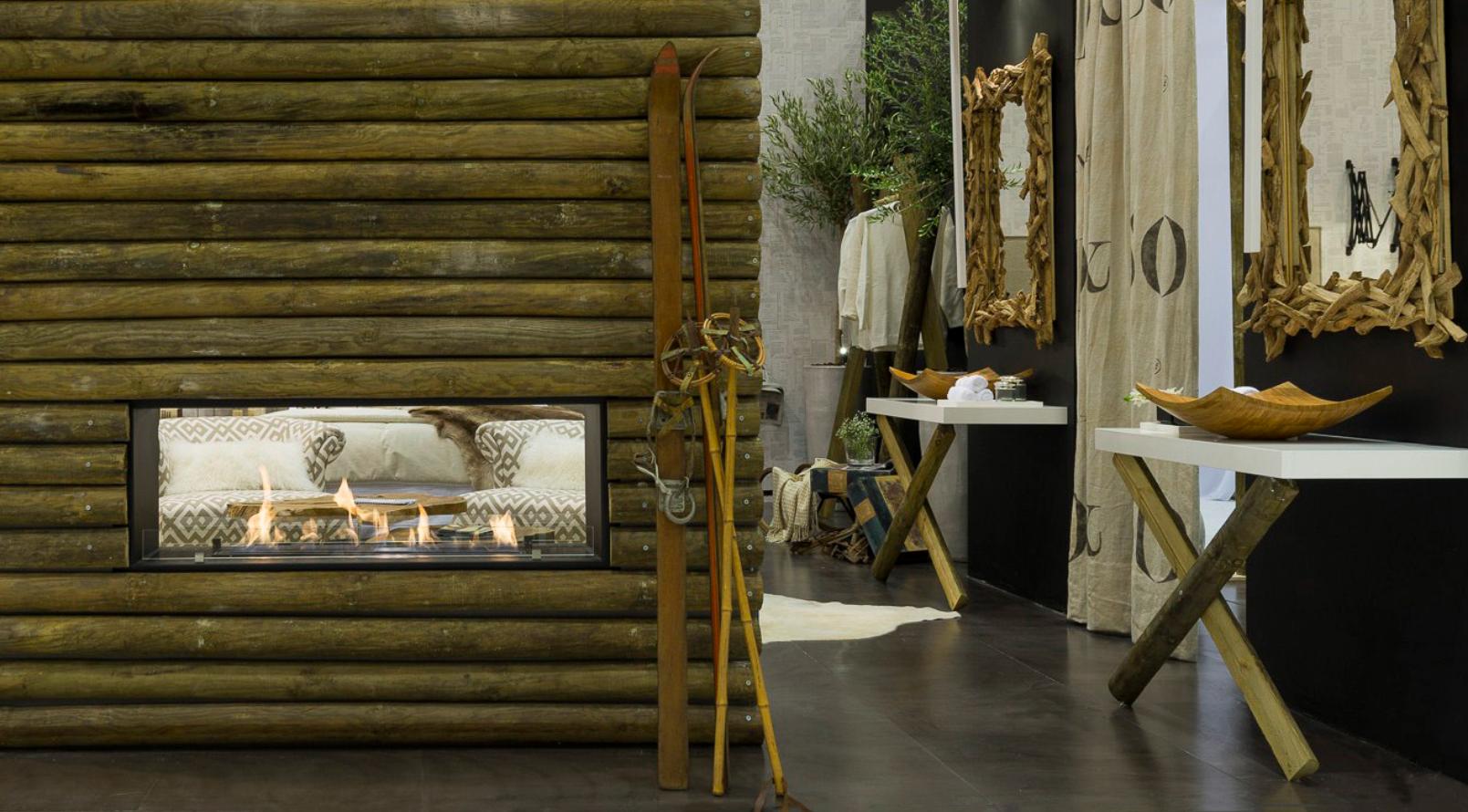 Decoração de quarto em tons neutros com recurso a tecidos muito confortáveis e de fibras naturais. A lareira forrada a troncos é a peça chave do quart