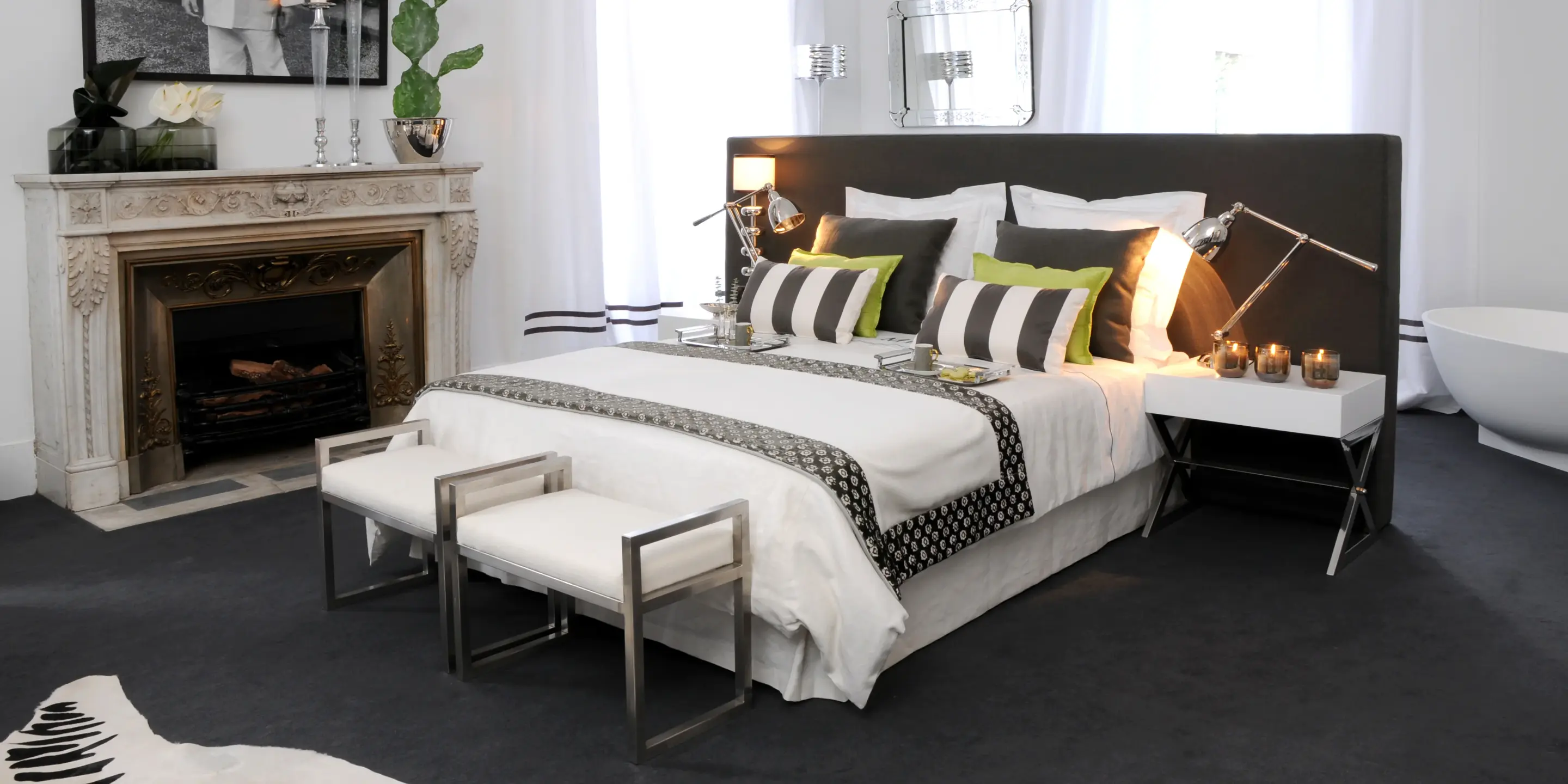 Suite em tons de cinza e branco em que o mobiliário contemporâneo contrasta harmoniosamente com os detalhes arquitetônicos dos tetos decorados. 