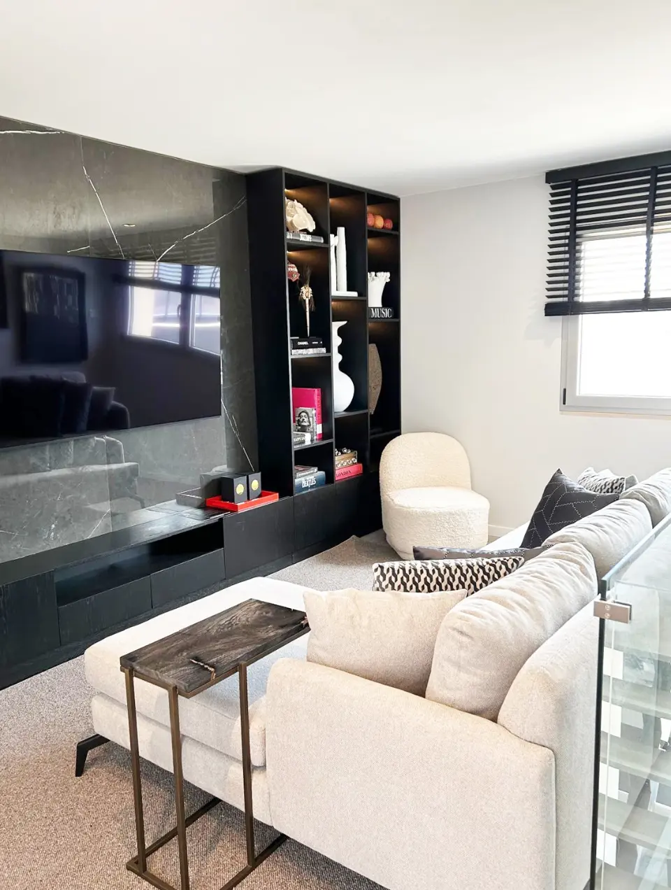 Contemporary living room interior design with large custom-designed bookcase with stone backing and niches with decorative pieces