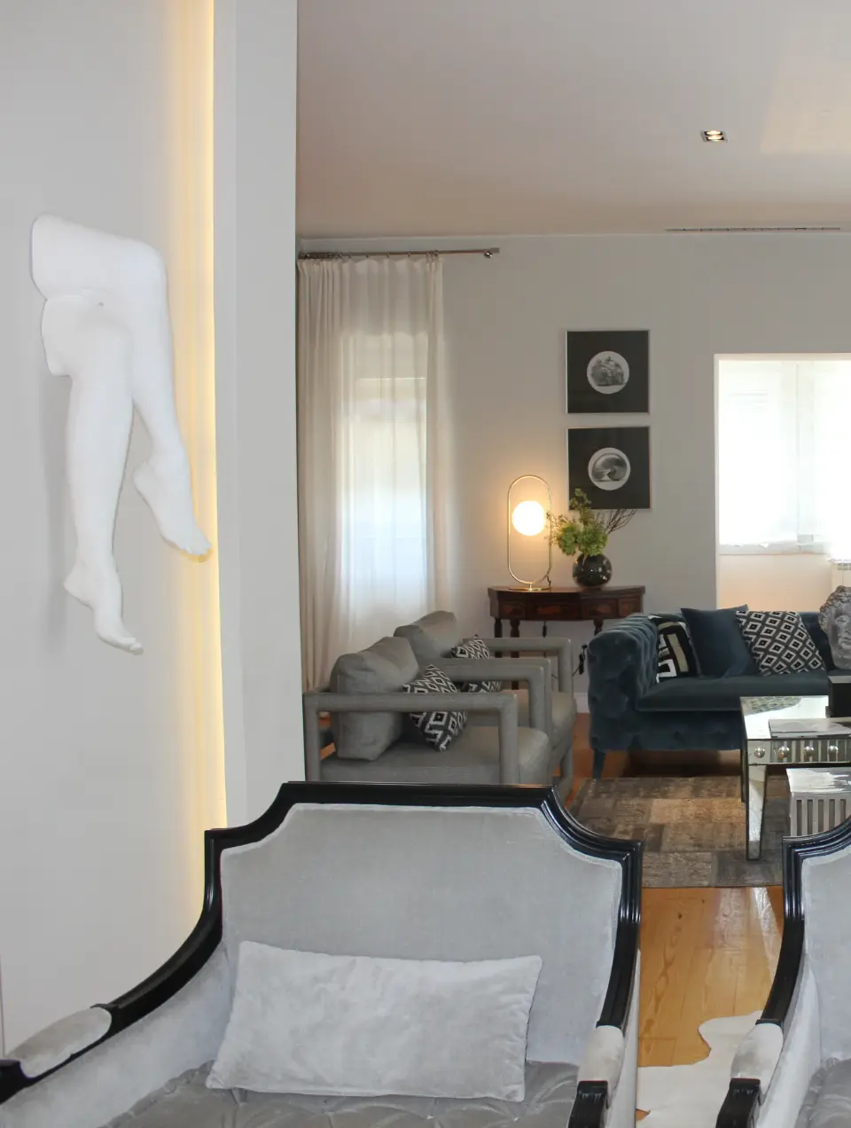 Decoração de sala de estar onde elegante escultura de pernas idealizada por Margarida Bugarim é a grande protagonista.