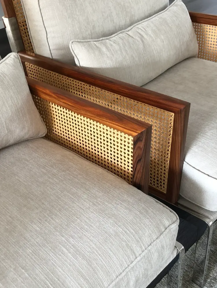 Detalhe de cadeirão estofado, com pé em aço inox e braço em madeira e palhinha integrado pela Margarida Bugarim Interiores num projeto de decoração.