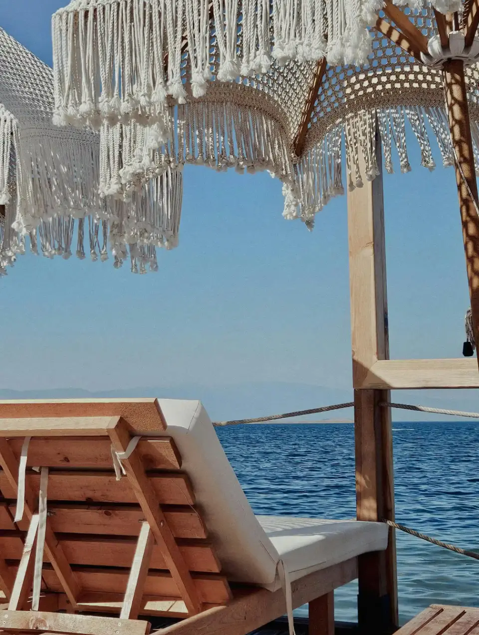 Paisagem de mar com espreguiçadeira e chapéu de som em macramé