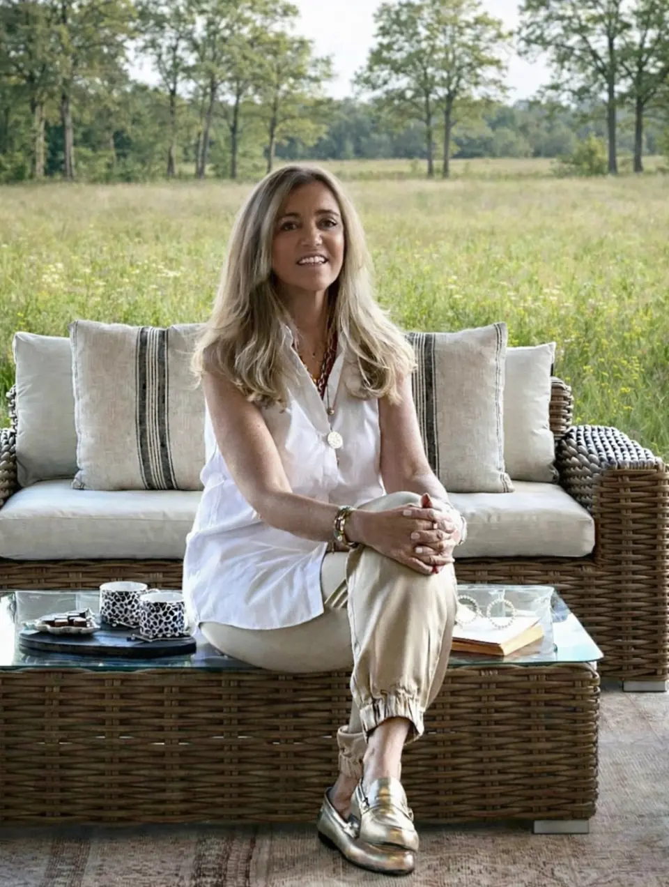 Arquiteta Margarida Bugarim em terraço com sofá de rattan castanho decorado com almofadas de linho com riscas
