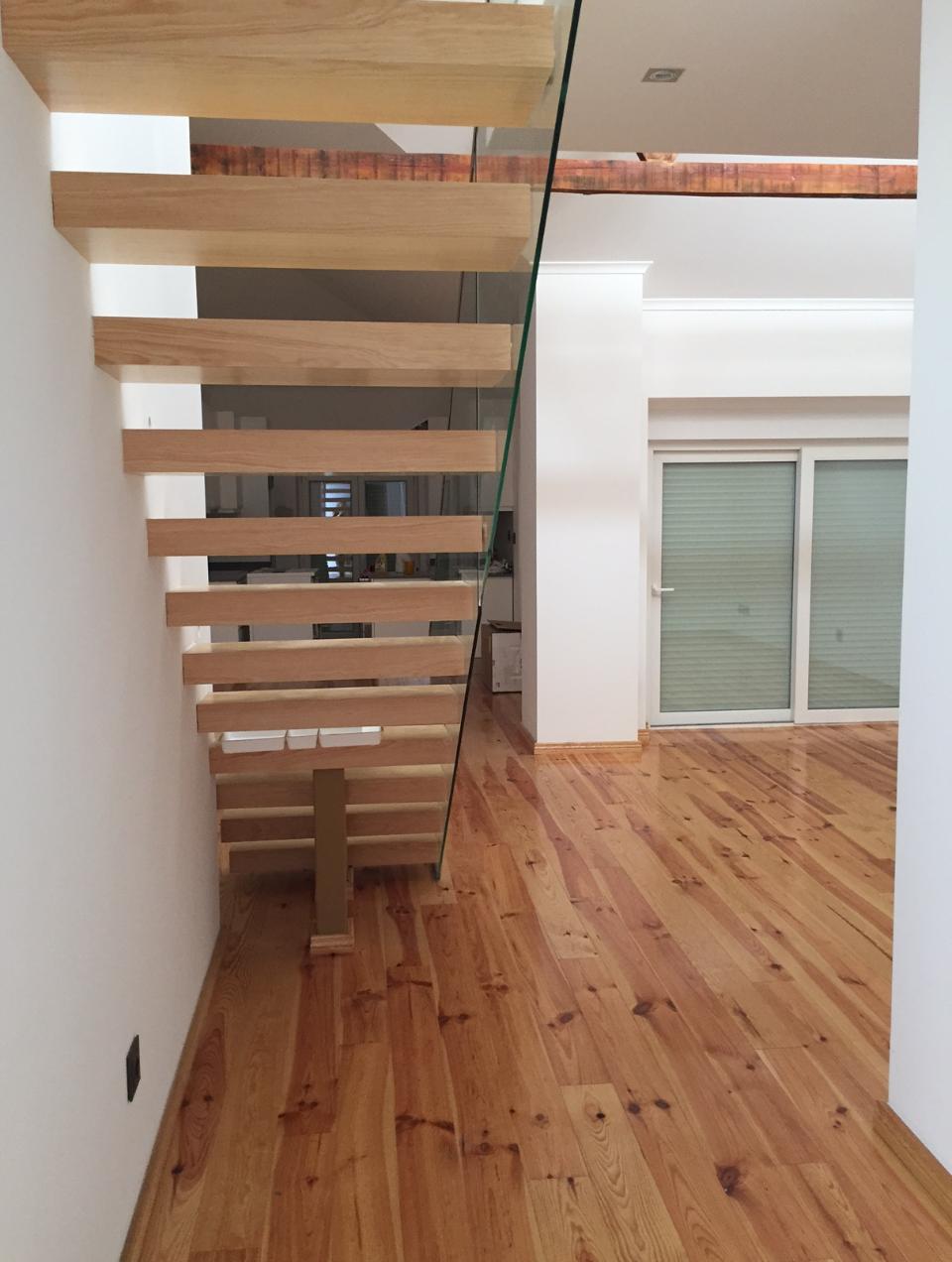Apartment renovated by Margarida Bugarim Interiores, featuring white-painted walls, hardwood flooring, and an oak staircase