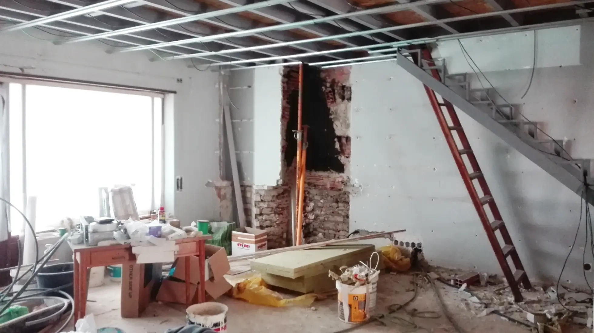 Sala em obras de um apartamento duplex, remodelação total que incluiu alteração de lareira e escadas de acesso ao piso superior