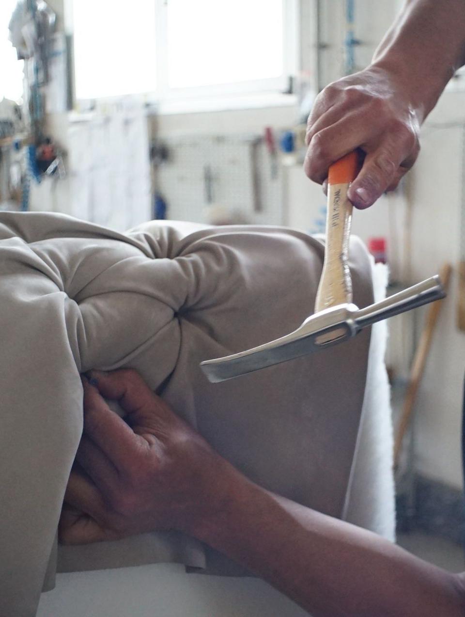 Upholsterer from the Margarida Bugarim Interiors team upholstering a sofa armrest with a tufted design