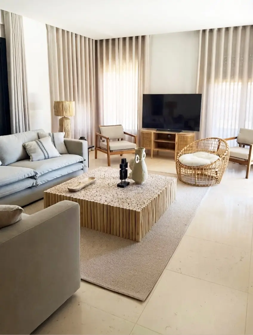 Decoração de sala em tons neutros com sofá em L beige, tapete em lã e mesa de centro de troncos