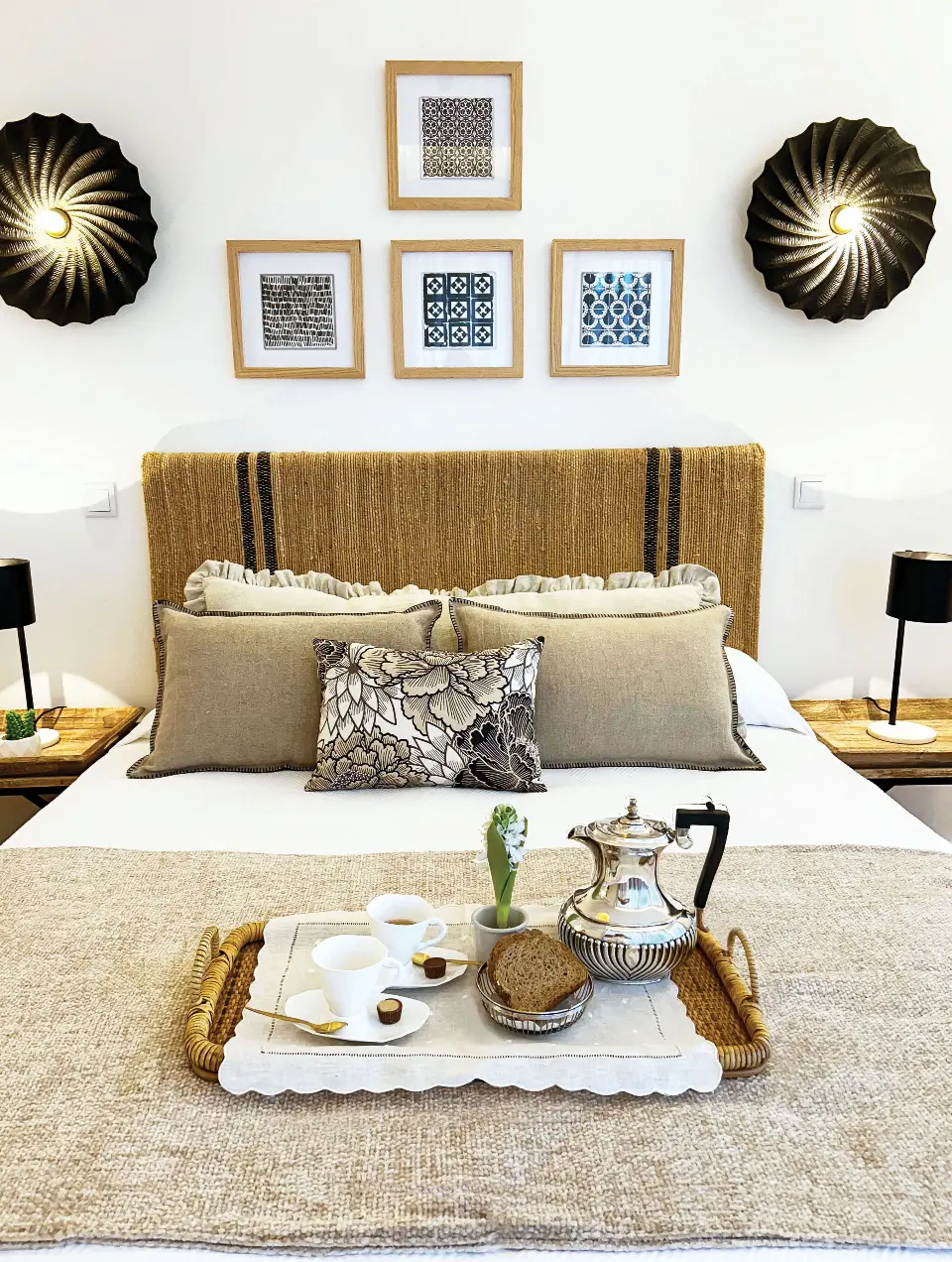 Suite com cabeceira de cama em corda natural com riscas pretas, apliques redondos pretos e muitas almofadas de tons neutros