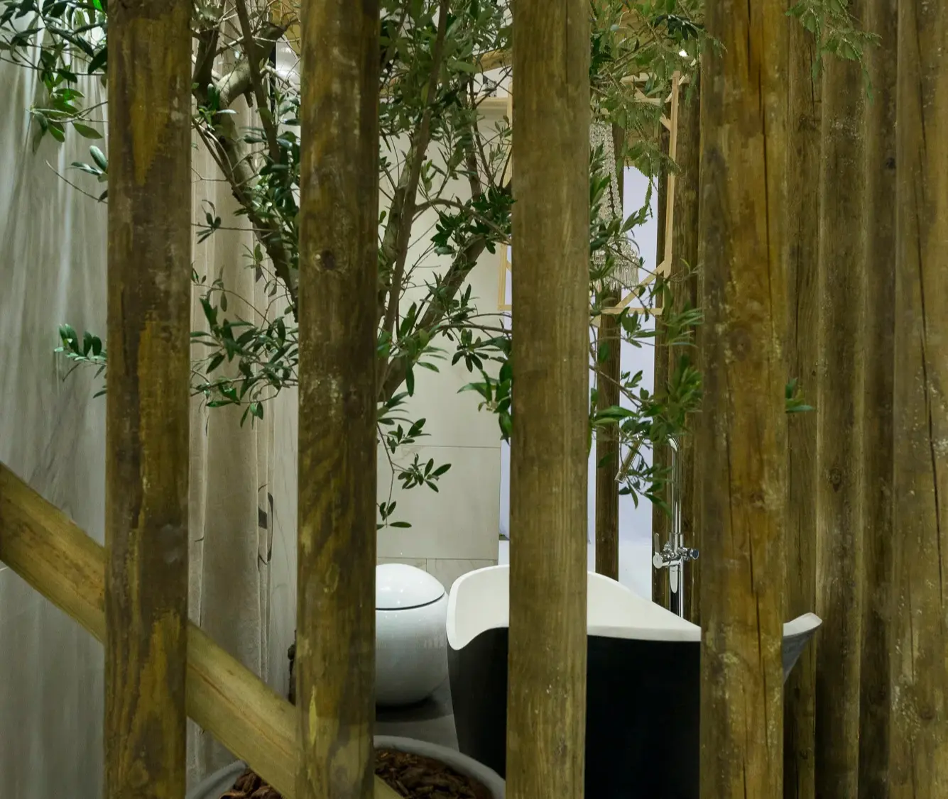 Detail of bathroom surrounded by rustic logs, with black freestanding bathtub and round toilet