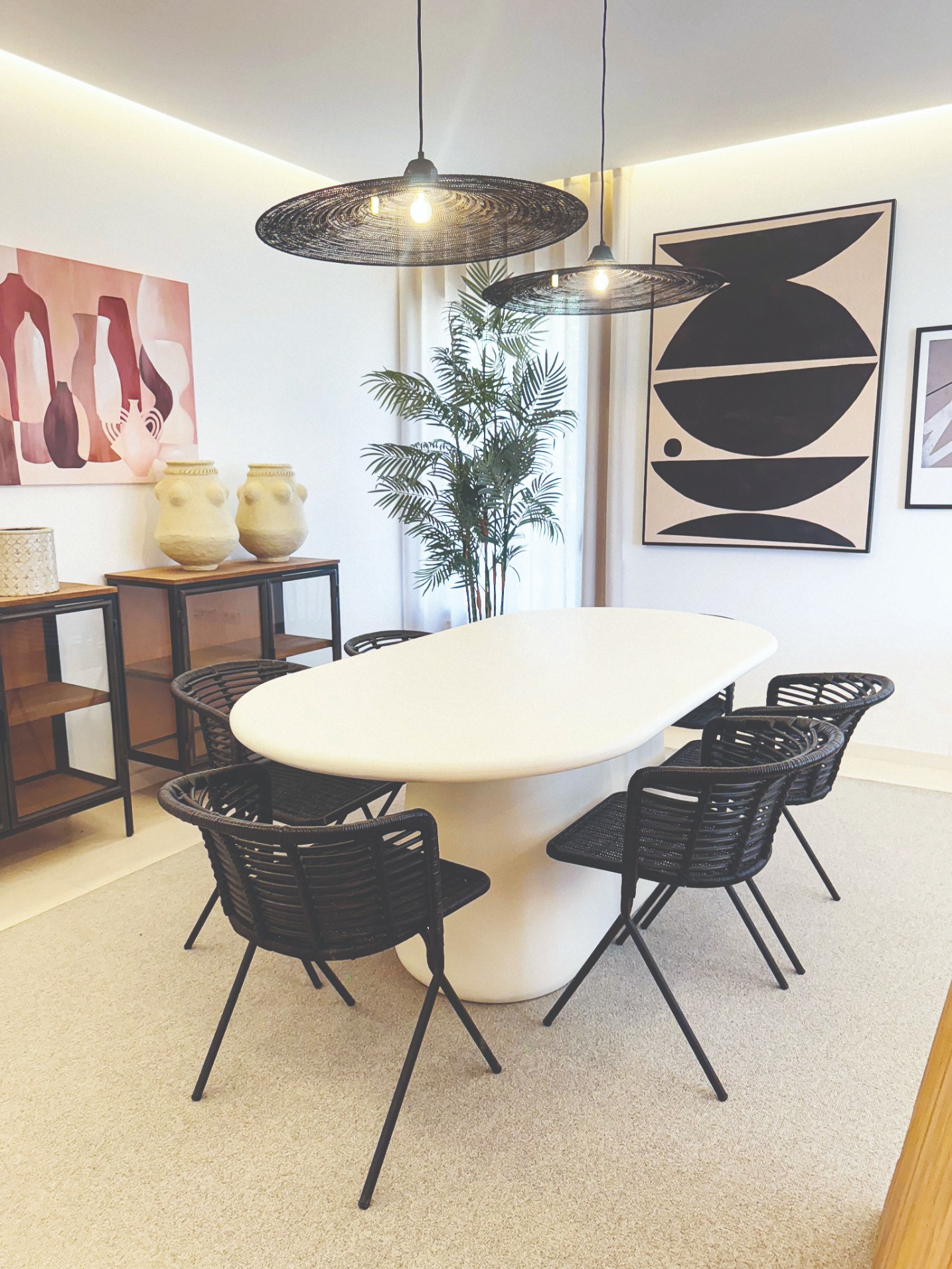 Sala de jantar de apartamento com mesa branca, cadeiras em corda preta e aparadores em madeira
