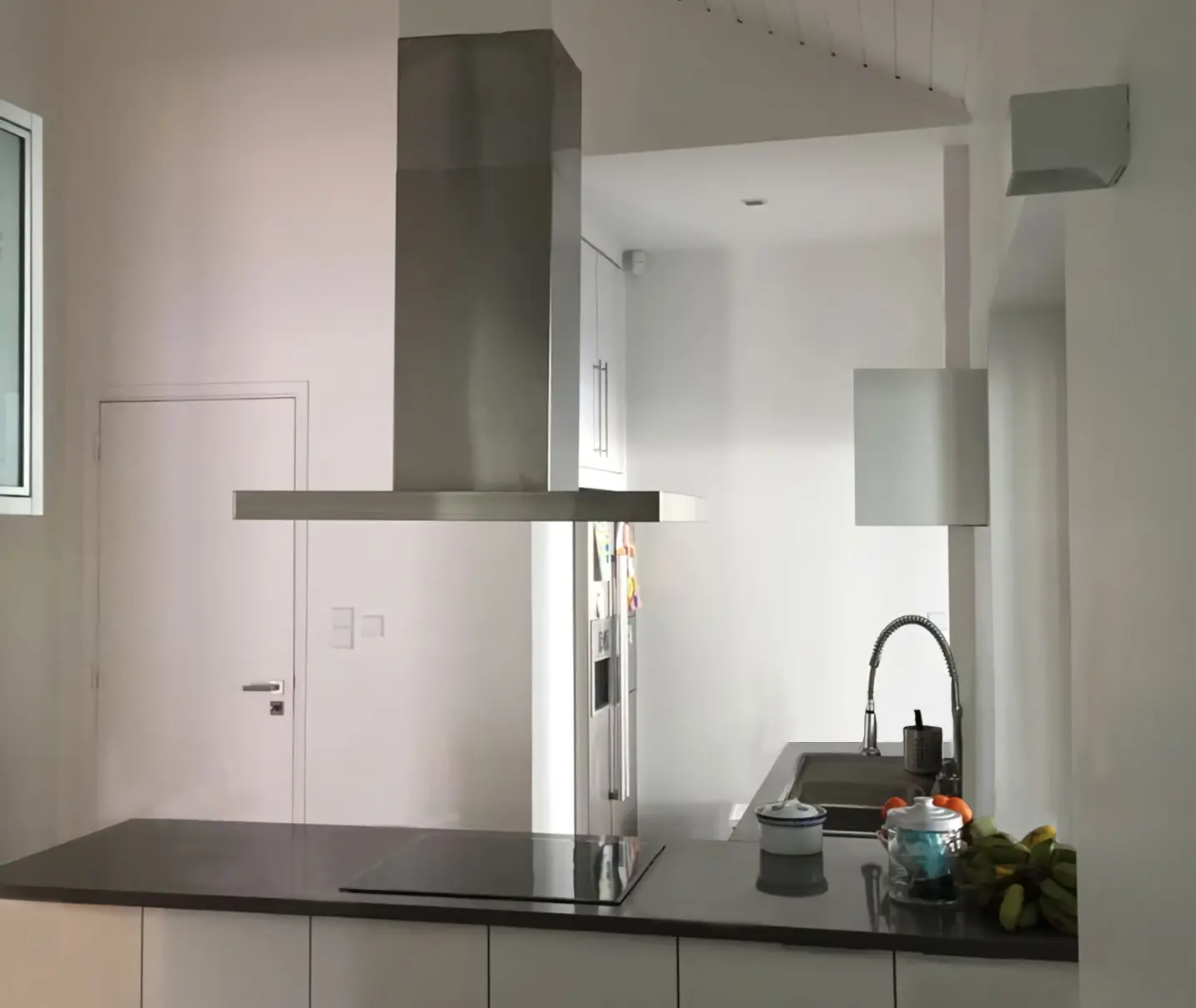 Cozinha contemporânea lacada branca desenhada por medida pela Margarida Bugarim Interiores  com península e exaustor de teto em aço inox