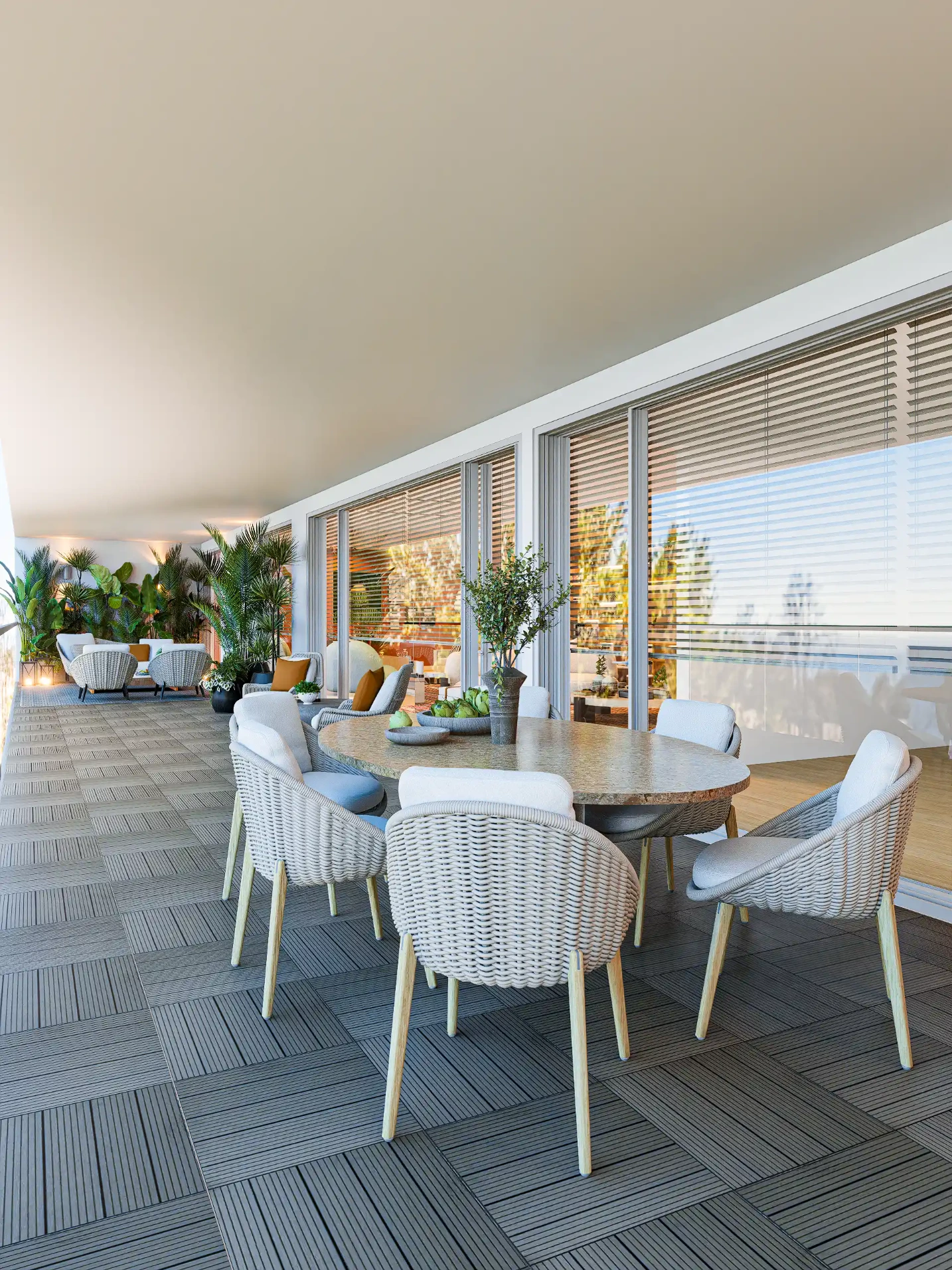 Dining area on the terrace with oval stone table, light rope chairs with white cushions, decorative plants, and direct connection to the living room