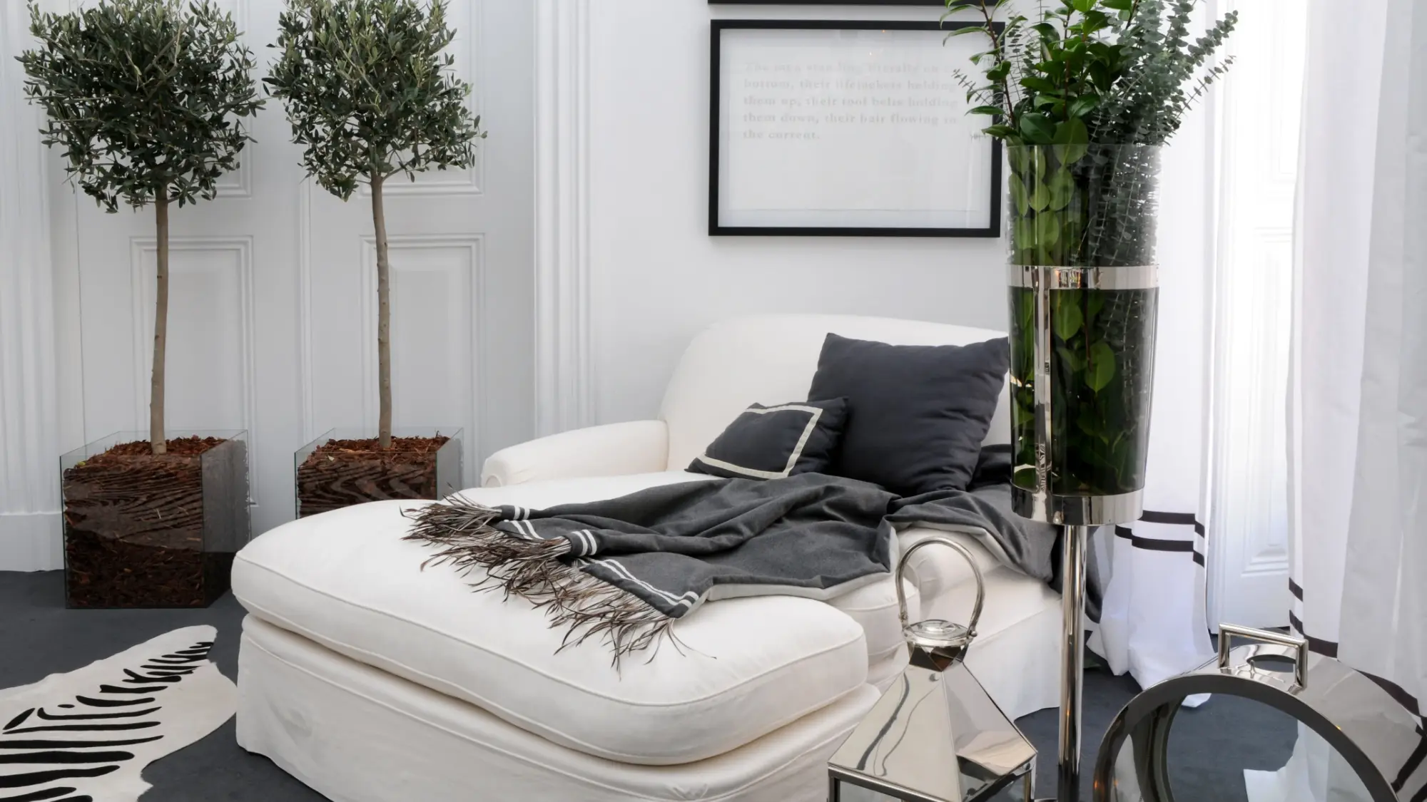 Zona de leitura elegante com chaise-longue branca e arranjos de vegetação – decoração de interiores com estilo contemporâneo e elementos naturais