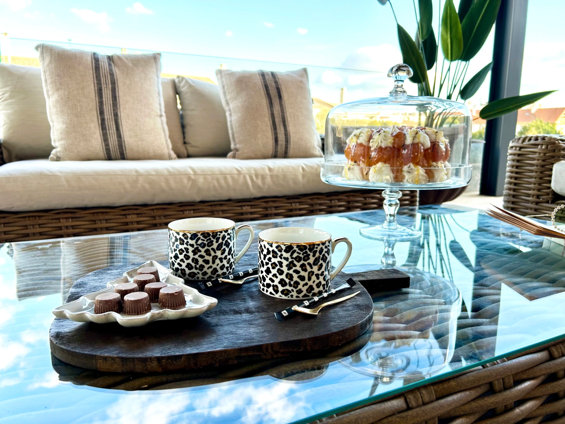 Decoração de terraço com sofás em ratan sintético castanho, lanternas e plantantas tropicais