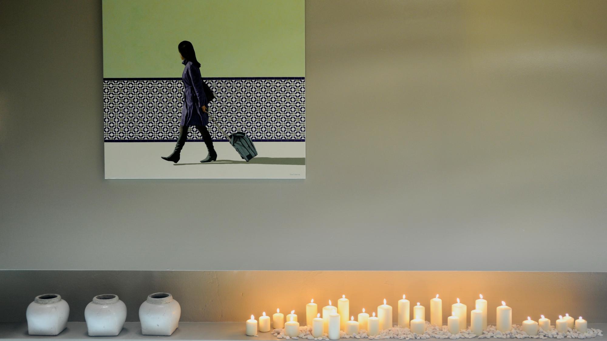 Parede com obra de arte contemporânea de figura feminina em movimento, velas brancos e três vasos cerâmicos, decoração assinada por Margarida Bugarim