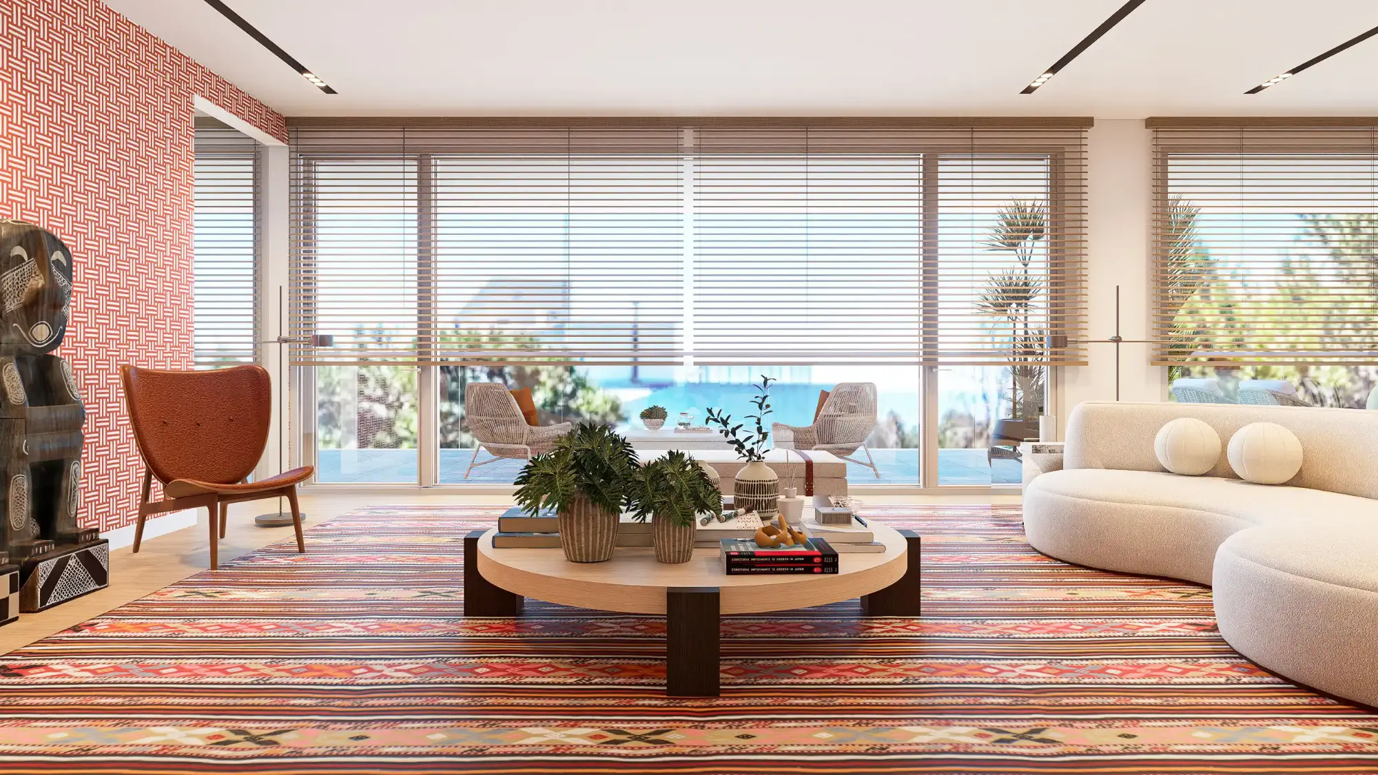 Sala de estar com amplas janelas e vista mar, sofá curvo branco, tapete étnico colorido e cadeirões de design em pele